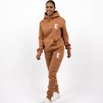 Model wearing a light brown sweat suit. The model is also wearing white sneakers. The sweat suit has the E's Element logo imprinted in white. E's Element Essential Brown Sugar Sweatsuit Set by E's Element.