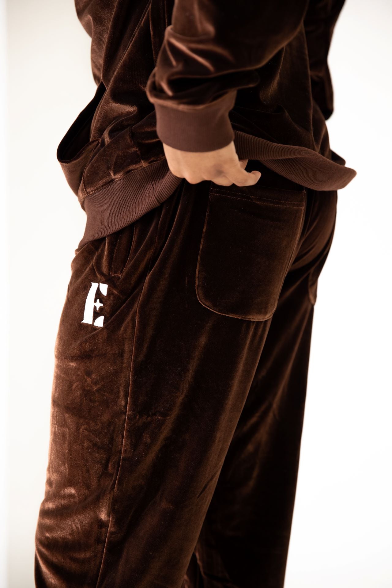 Model wearing dark brown velvet joggers. The joggers have the E's Element logo imprinted in white.