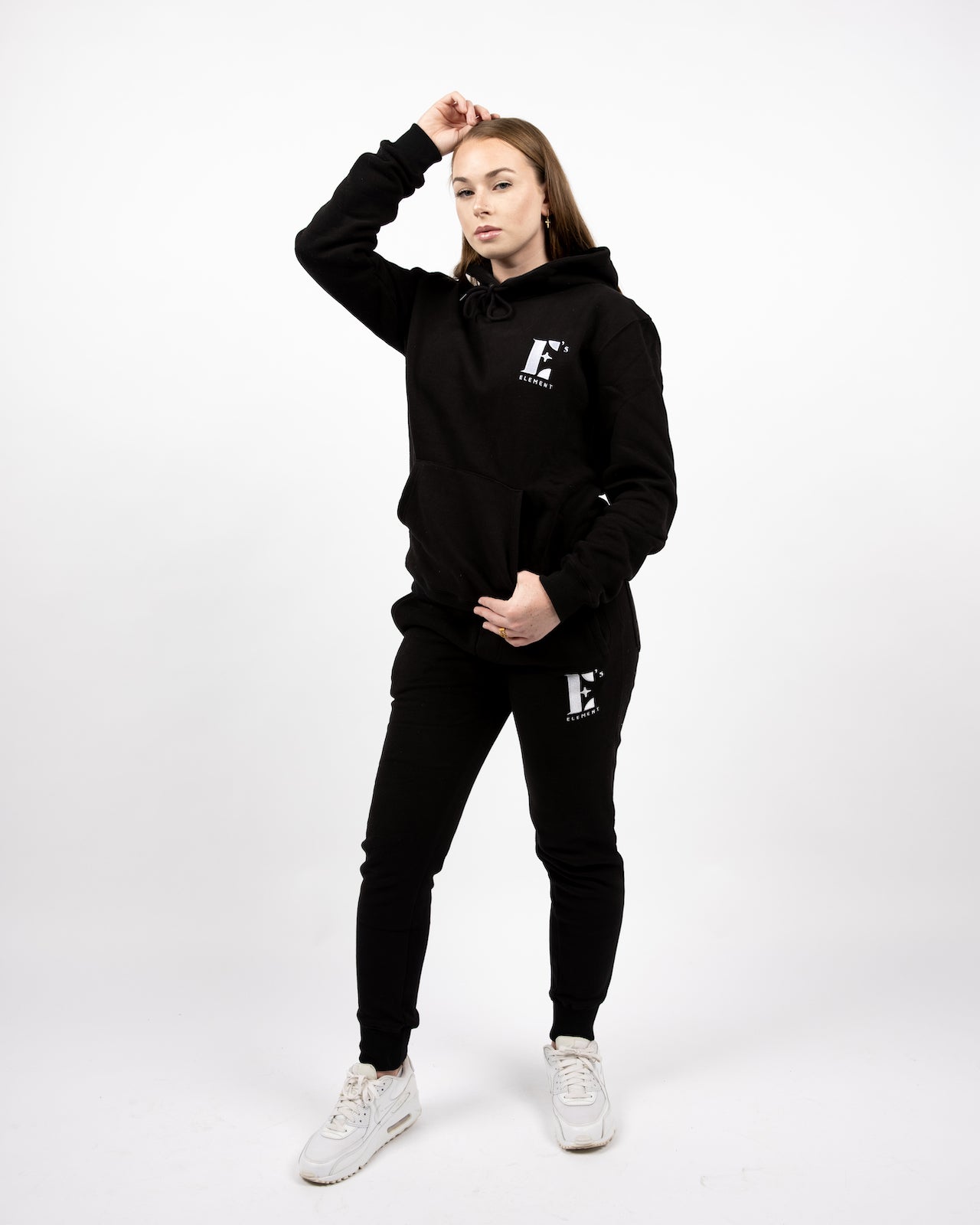 Model wearing a black sweat suit. The hoodie and sweat pants have the E's Element logo imprinted in white. E's Element Essential Smoky Black Sweatsuit Set by E's Element.