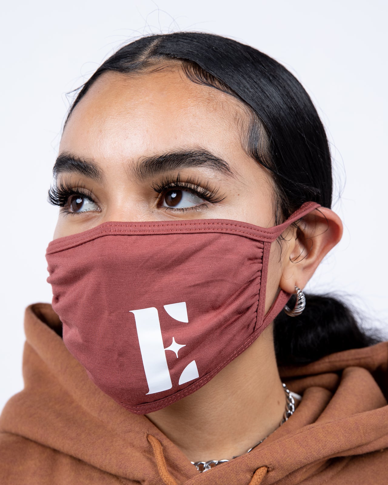 Model in a brown hoodie wearing light brown reusable face mask. The face mask has the E's Element logo imprinted in white. Spice Face Mask by E's Element.