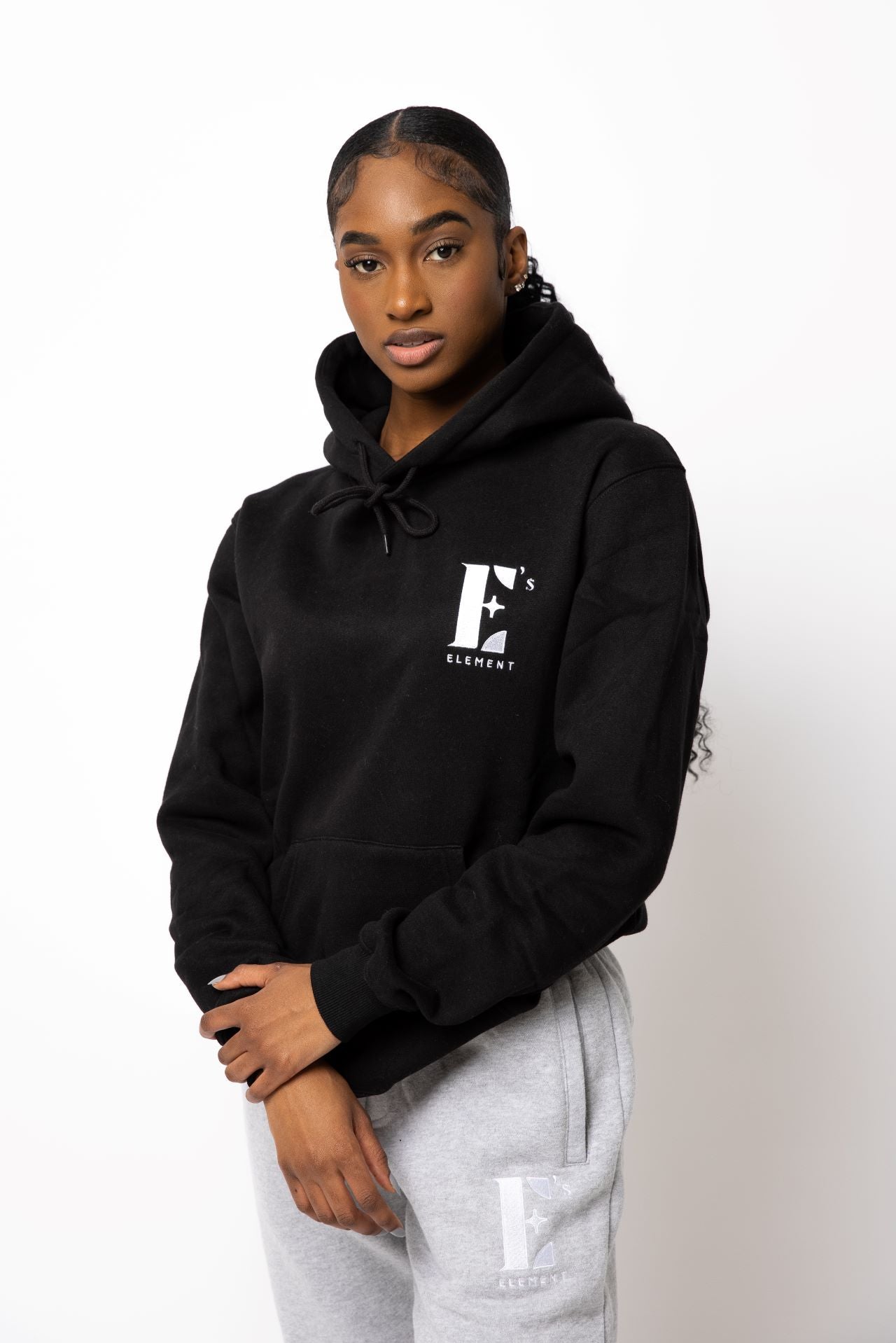 Model wearing a black hoodie. The hoodie has the E's Element logo imprinted in white. E's Element Essential Smoky Black Sweatsuit Set by E's Element.