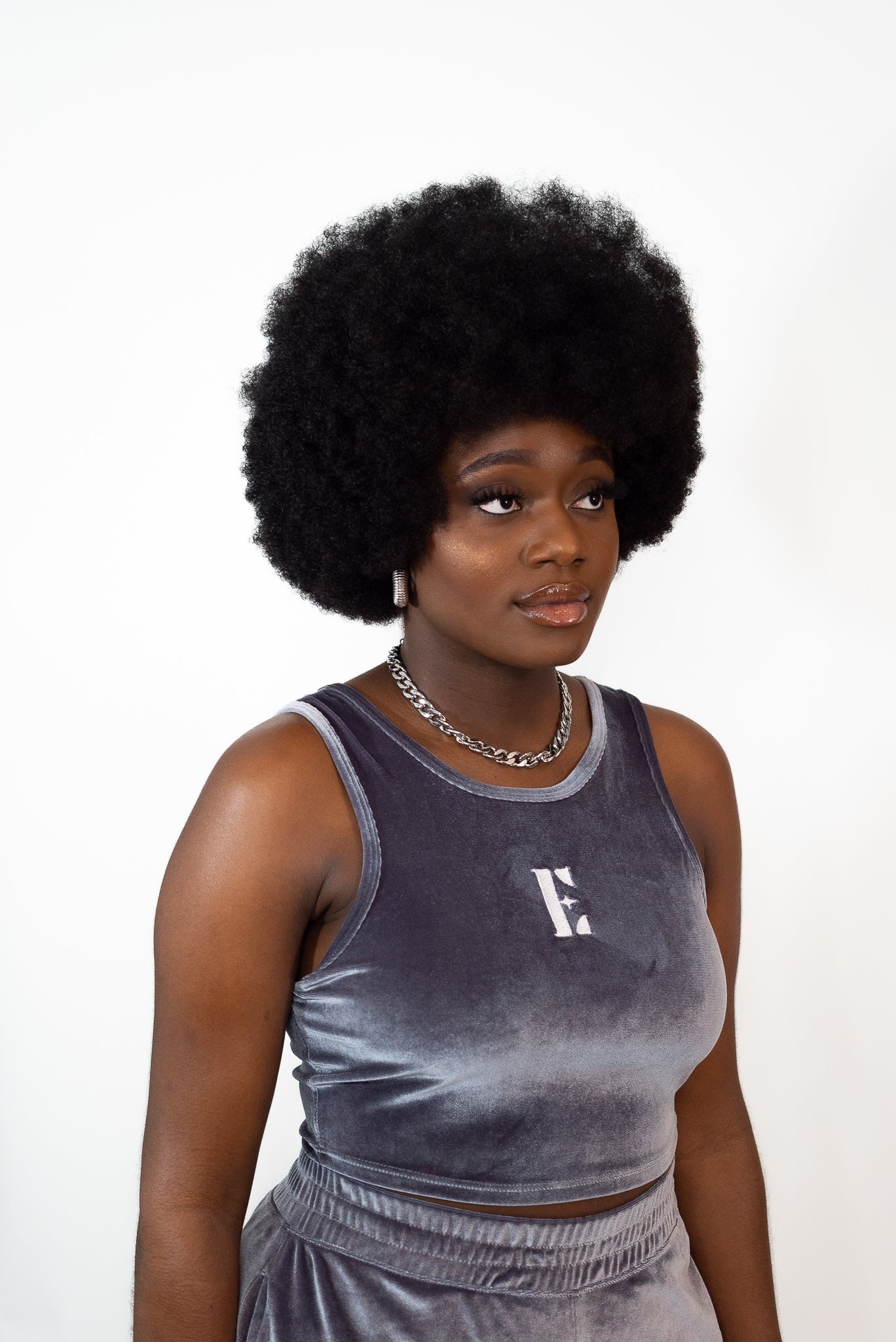 Model wearing grey velvet crop top and shorts. The crop top has the E's Element imprinted in white in the center. The model is also wearing an 18k silver stainless steel chain necklace and hoop earrings. Ella Icy Blue Velvet Set by E's Element.