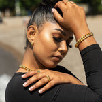 Model in a black top wearing 18k gold chain necklace and bracelet. She is also wearing 18k gold rings. The Emmanuela Set in Gold by E's Element.