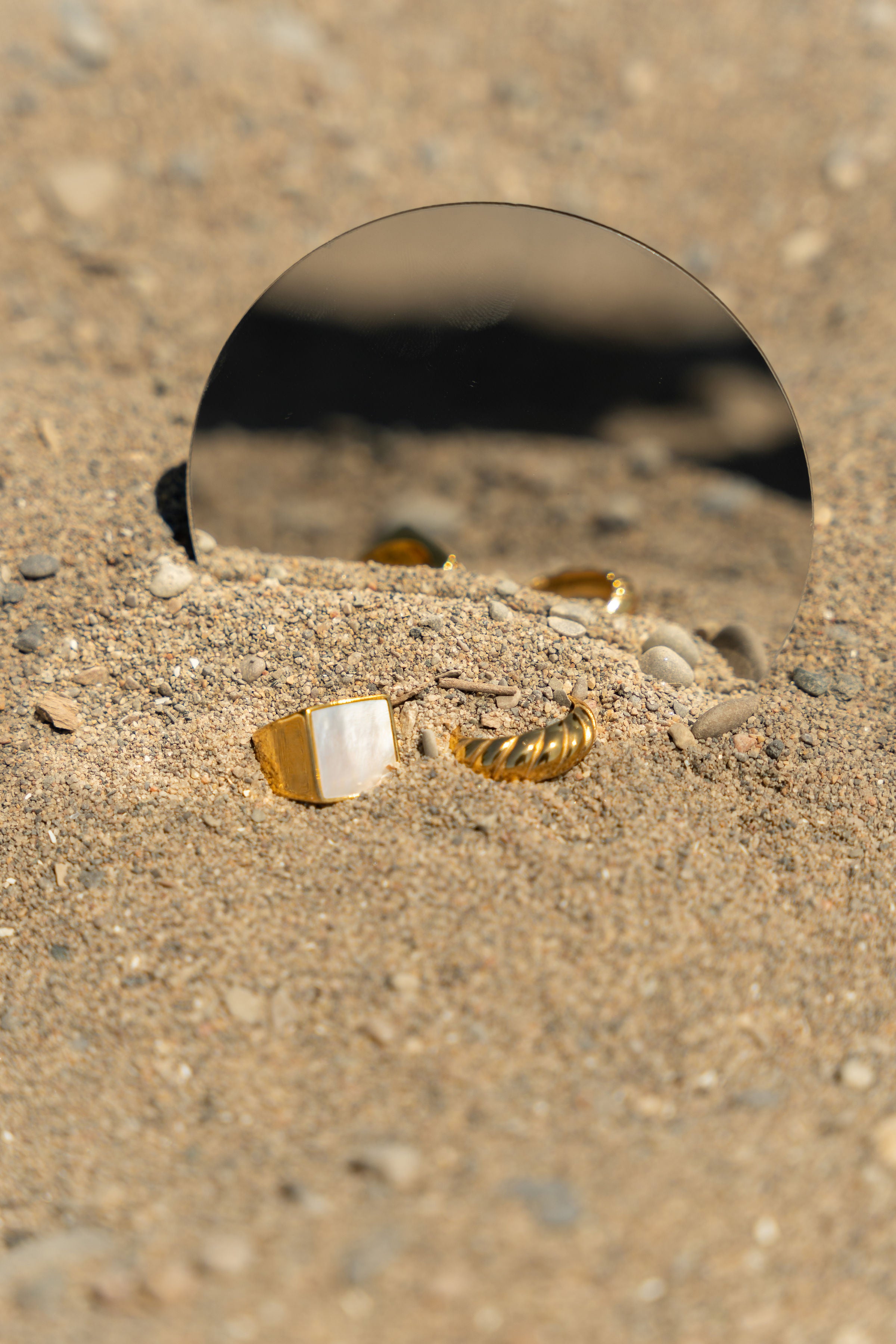 Two 18k gold stainless steel rings placed in front of  a mirror. Build Your Own Ring Set by E's Element.