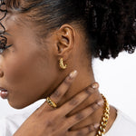 Model wearing 18k gold croissant shaped earrings. She is also wearing a gold ring and chain necklace. Thick Croissant Stud Earrings - E's Element.