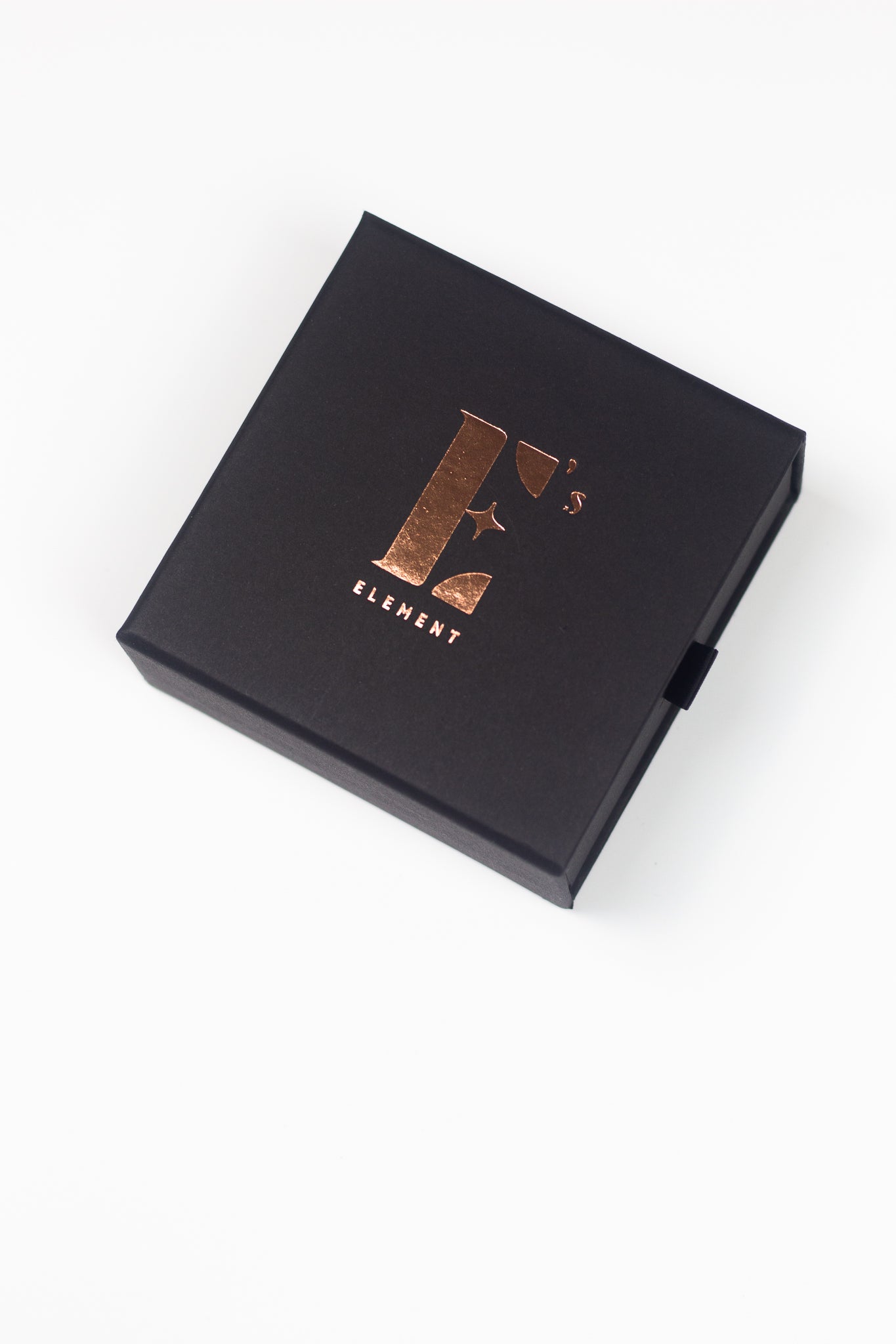 Cap of a box in black. The cap has the E's Element logo imprinted in gold. Gift Box (Add-On) by E's Element.