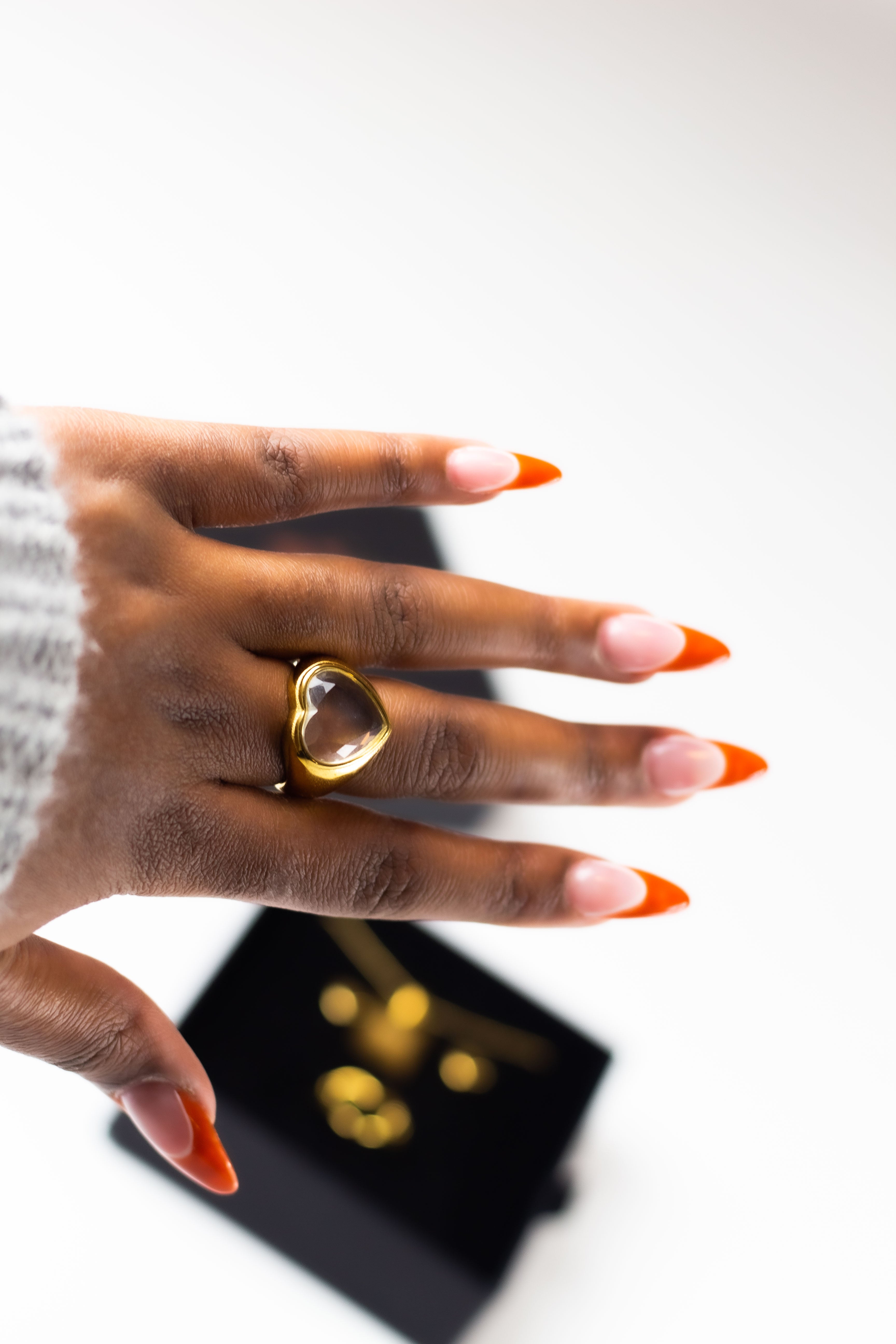 Model wearing an 18k gold ring with a heart shaped gem on the middle finger. Ella White Gemstone Ring by E's Element.