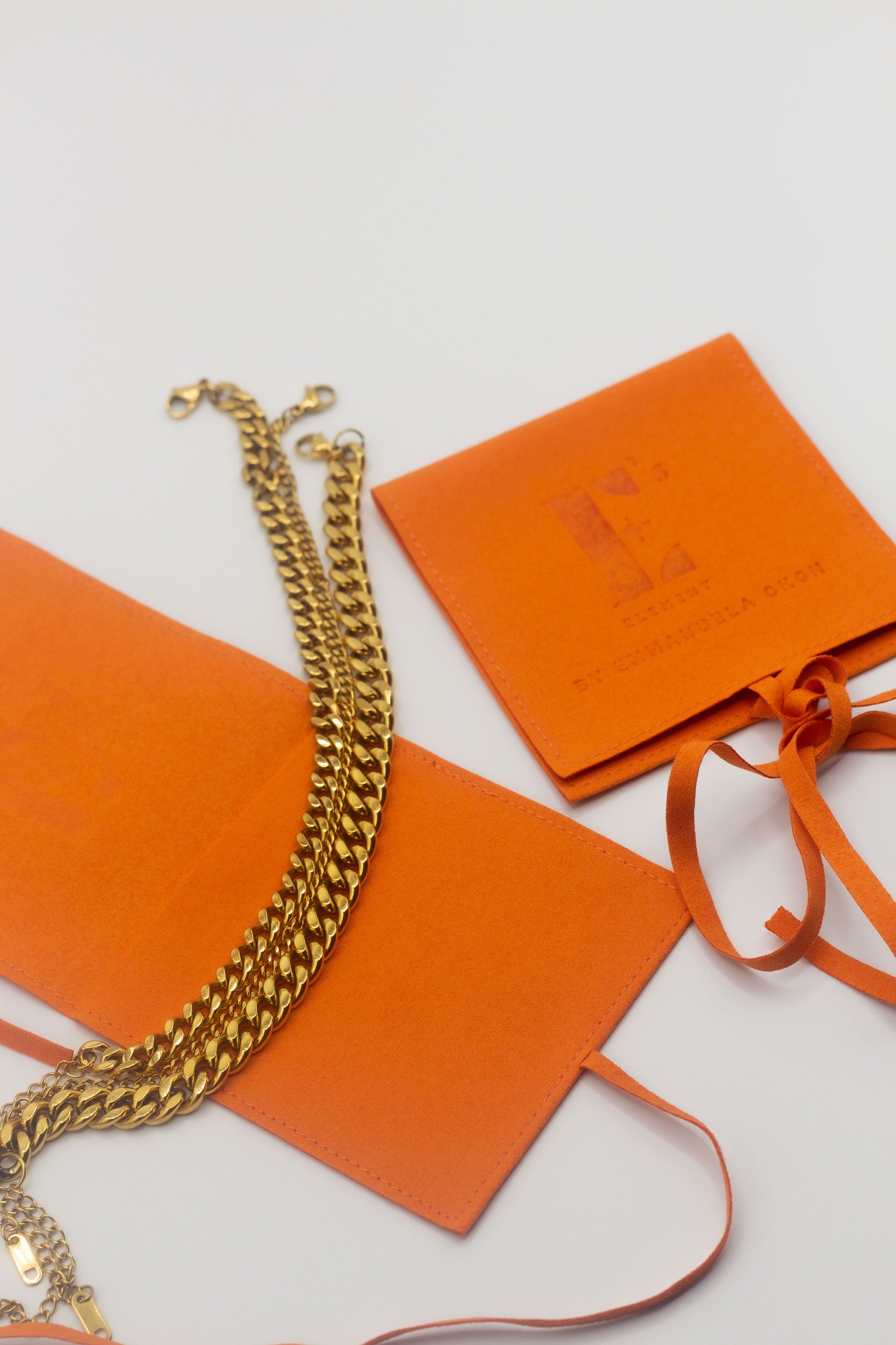 18k gold stainless steel chain anklet resting on top of a leather envelope. . Cuban Link Anklet by E's Element.