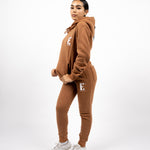 Model wearing a light brown sweat suit. The model is also wearing white sneakers. The sweat suit has the E's Element logo imprinted in white. E's Element Essential Brown Sugar Sweatsuit Set by E's Element.