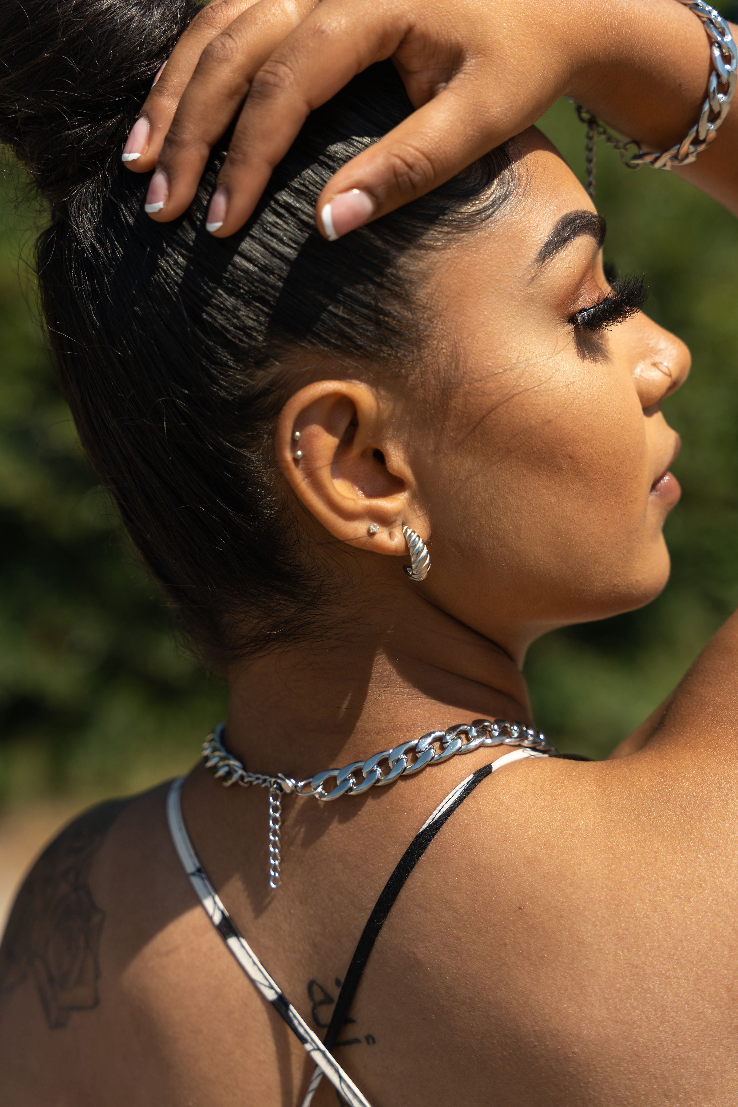 Woman in black and white bikini wearing E's Element Build Your Own Silver Jewelry Set. She is wearing stainless steel chain necklace, bracelet, and earrings.