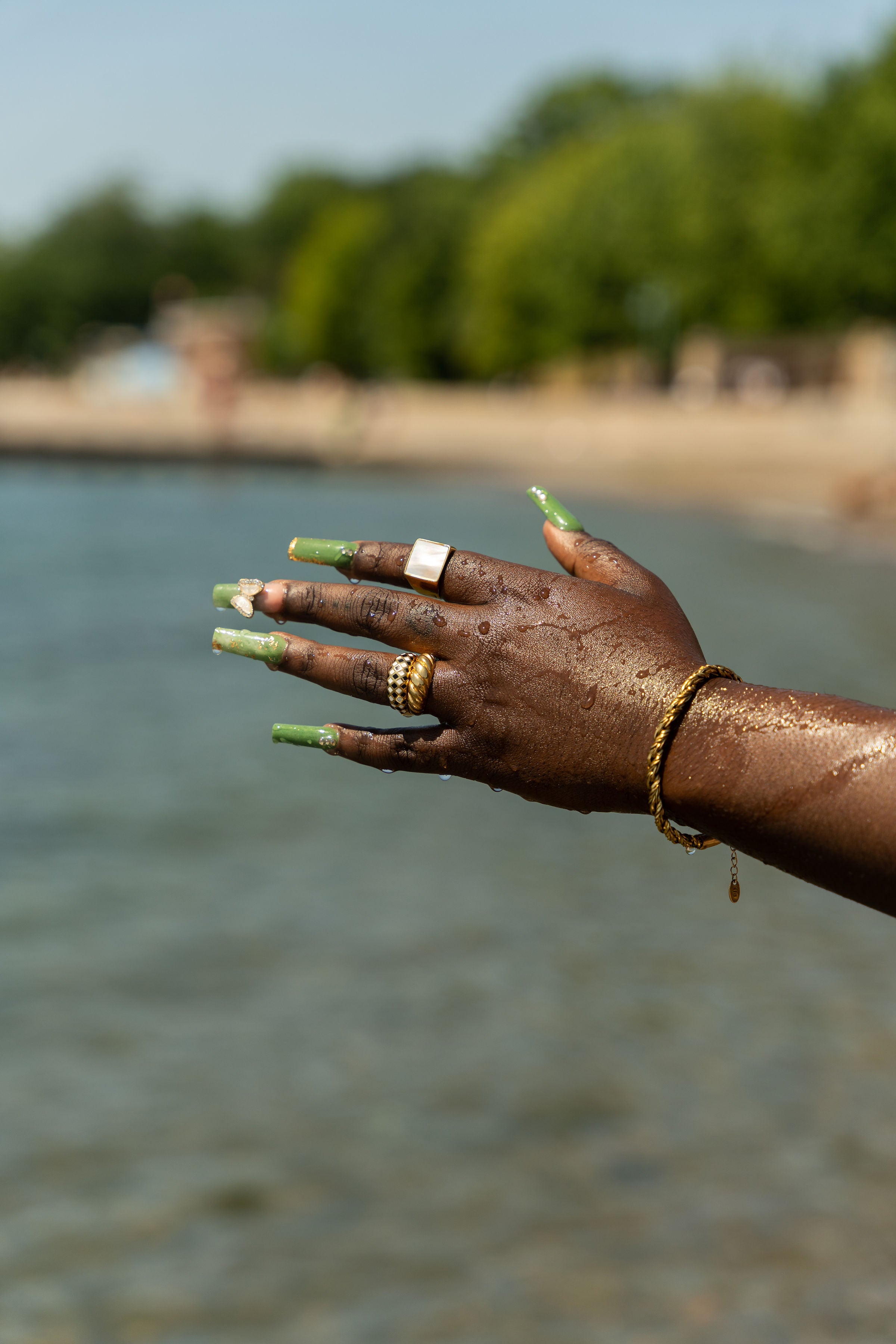 Woman wearing E's Element Build Your Own Ring Set. She is wearing an 18k gold stainless steel bracelet and four rings on the fingers.