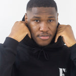 Model wearing a black hoodie. The hoodie has the E's Element logo imprinted in white. E's Element Essential Smoky Black Sweatsuit Set by E's Element.