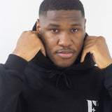 Model wearing a black hoodie. The hoodie has the E's Element logo imprinted in white. E's Element Essential Smoky Black Sweatsuit Set by E's Element.