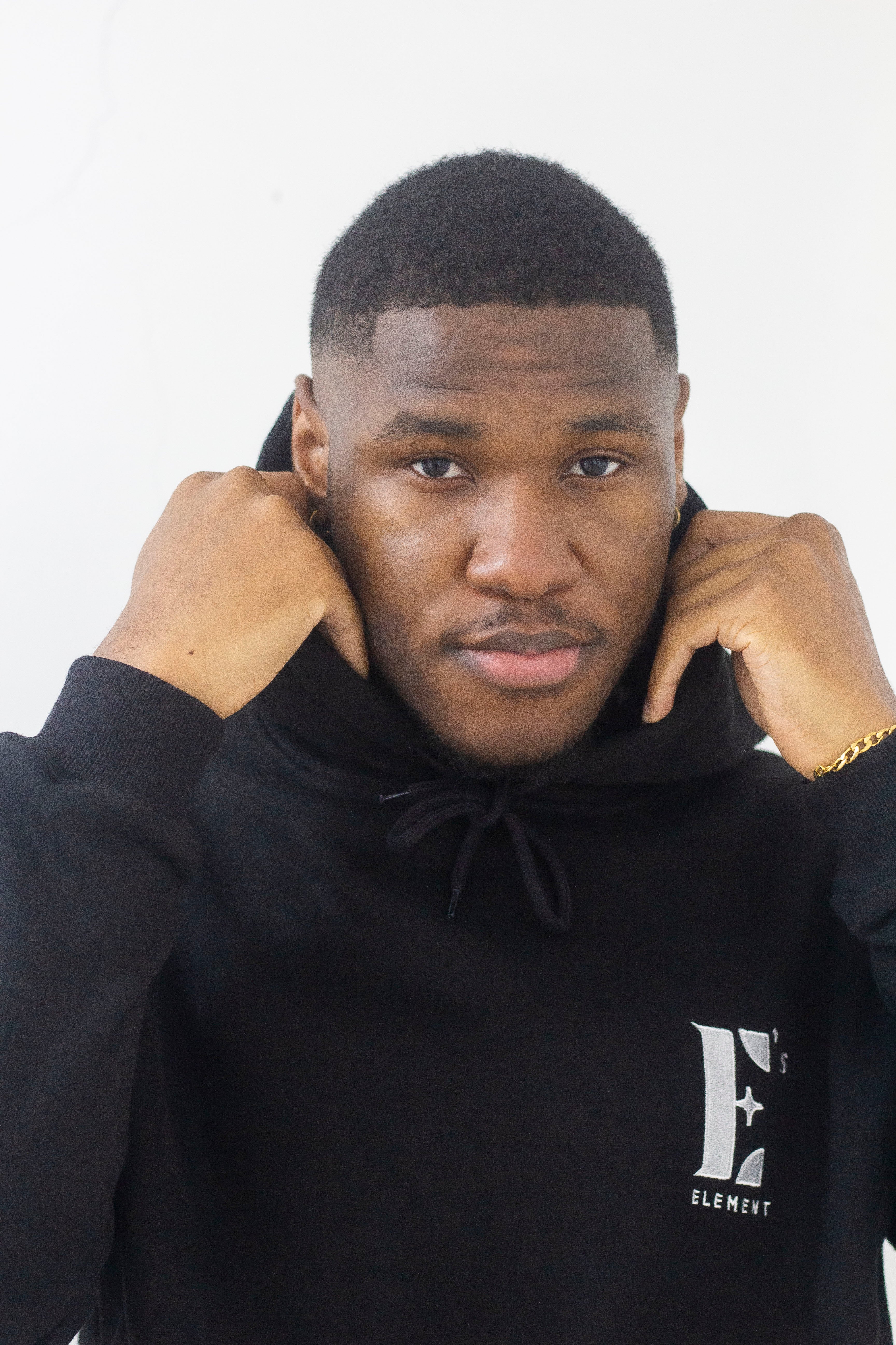 Model wearing a black hoodie. The hoodie has the E's Element logo imprinted in white. E's Element Essential Smoky Black Sweatsuit Set by E's Element.