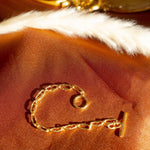 18k gold chain bracelet resting on an orange cloth. The bracelet has a hollow circle charm. Hollow Signature Chain Bracelet by E's Element by Emmanuela Okon.