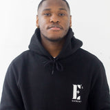Model wearing a black hoodie. The hoodie has the E's Element logo imprinted in white. E's Element Essential Smoky Black Sweatsuit Set by E's Element.