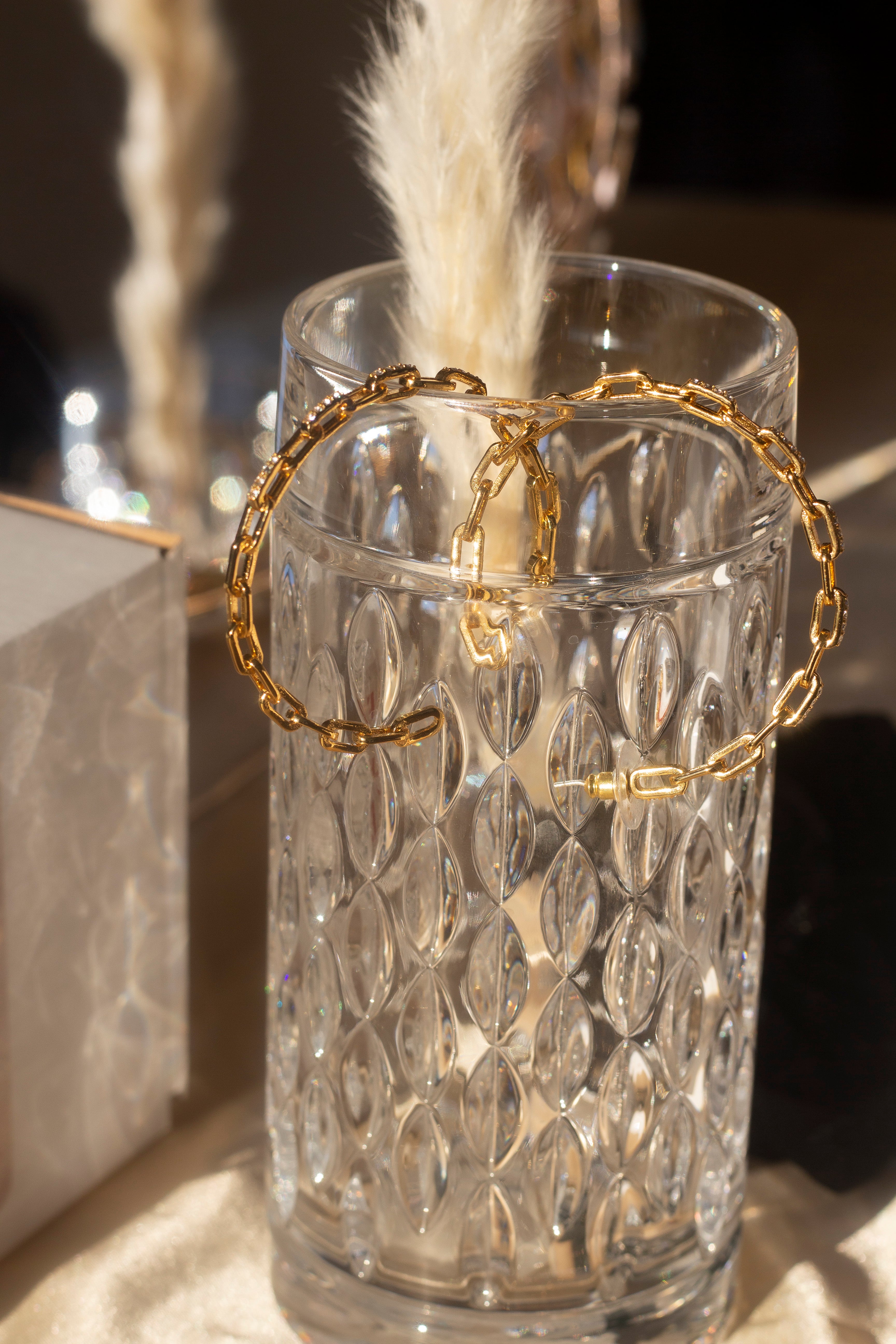 18k gold stainless steel Cubic Zircona hoop earrings hanging on the edge of a glass cup. . Ella Anchor Cubic Zirconia Hoops by E's Element.