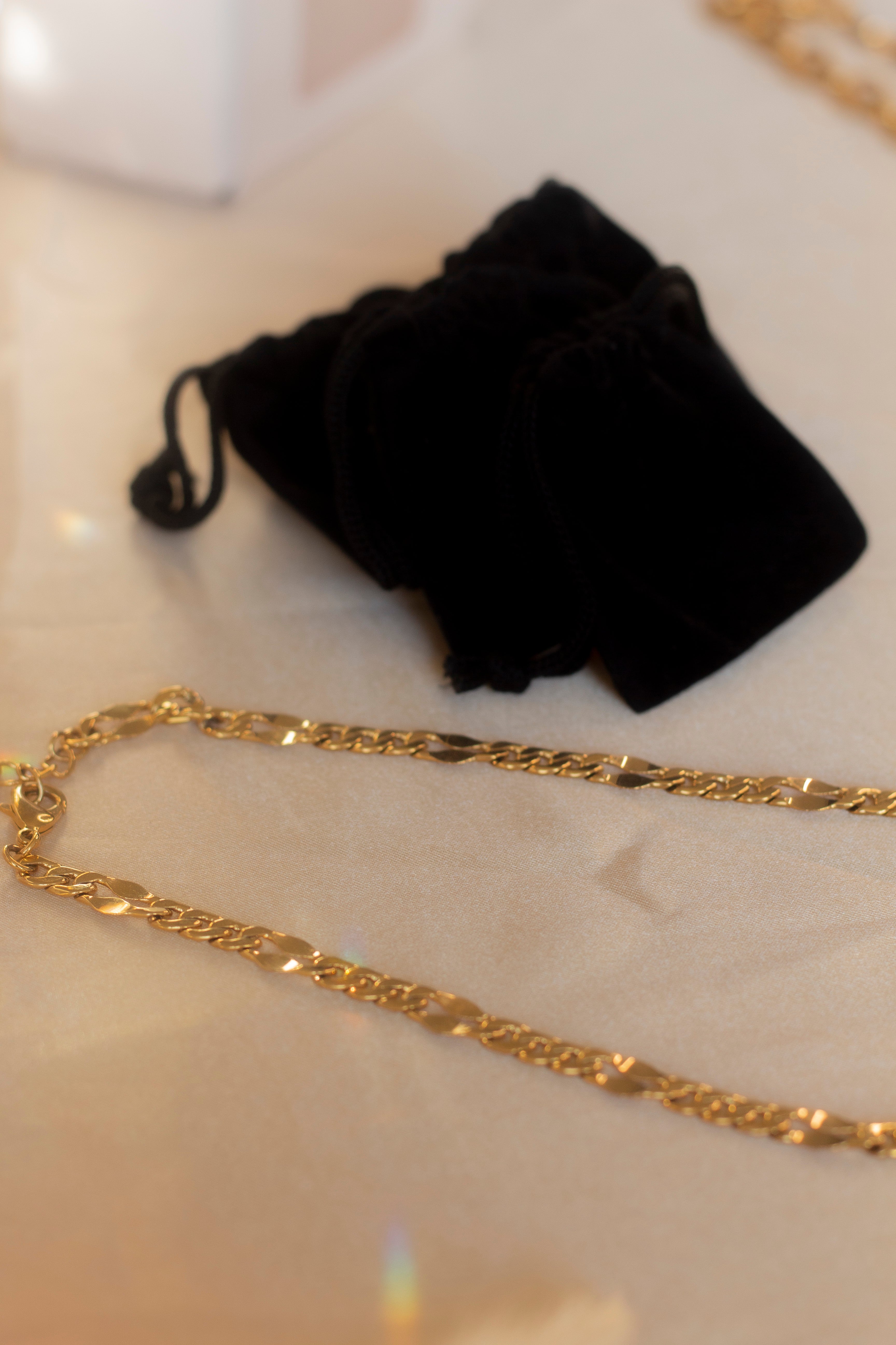 18k gold chain necklace placed on a beige cloth. Ella Figaro Necklace by E's Element.