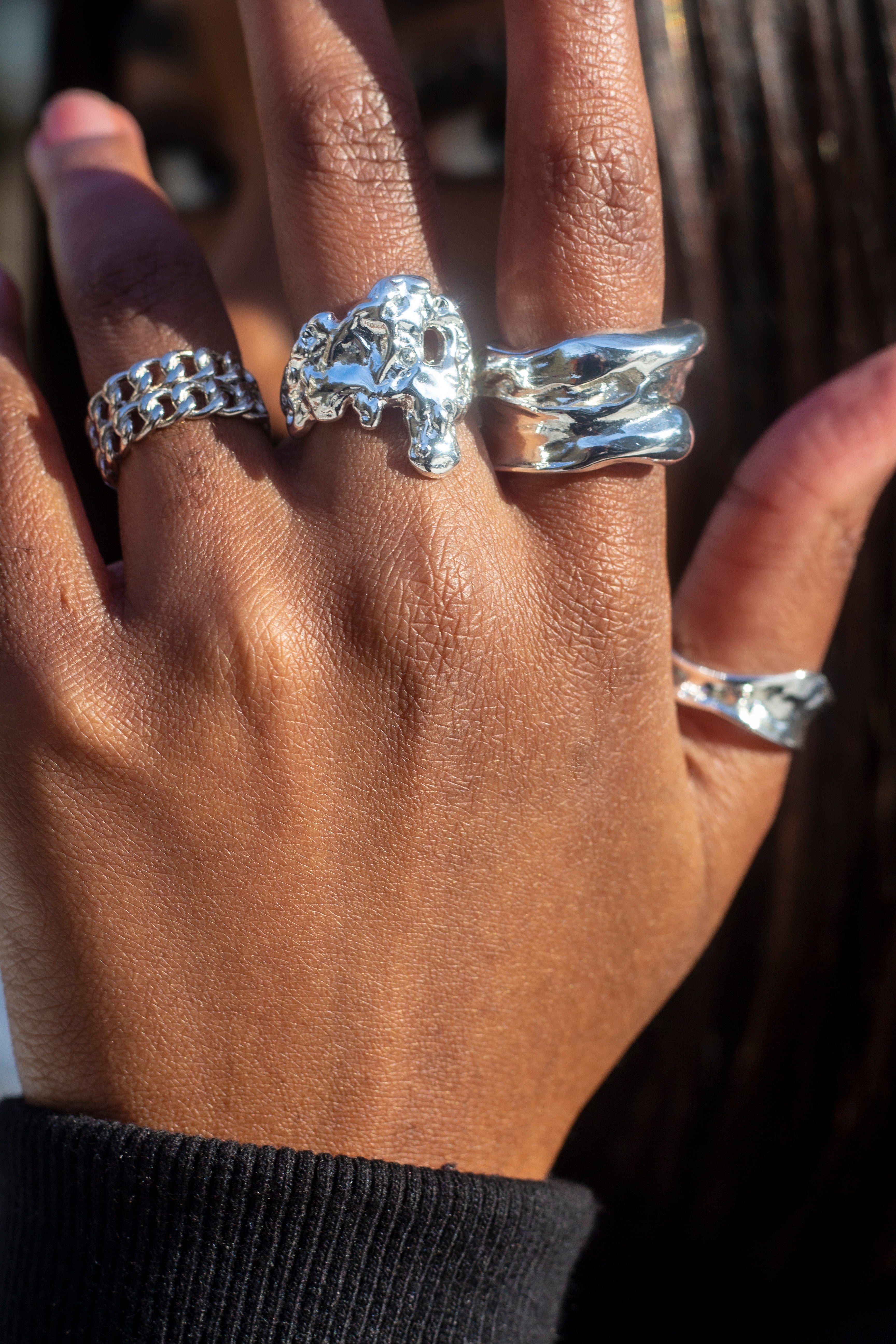 Model in a black top wearing 18k silver braided rings on her ring finger. She is also wearing silver rings on her middle, index, and thumb. Platinum Double Band Ring by E's Element.