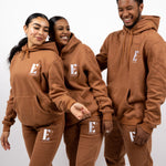 Three models wearing light brown track suits. The tracksuits have the E's Element logo imprinted in white. E's Element Essential Brown Sugar Sweat suit Set by E's Element.