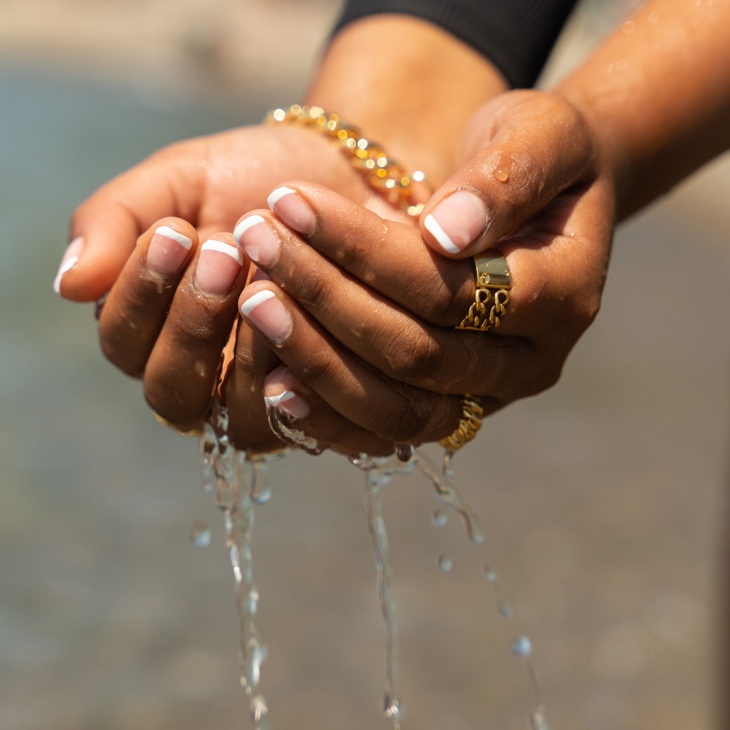 Woman wearing gold rings at the beach near water