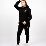 Model wearing a black sweat suit. The hoodie and sweat pants have the E's Element logo imprinted in white. E's Element Essential Smoky Black Sweatsuit Set by E's Element.