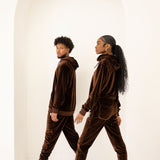 Photo of a male and female model posing in the e's element chocolate brown velvet jogger set. the male and female model is showing the side view of the jogger set.