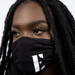 Model wearing a black reusable face mask. The face mask has the E's Element logo imprinted in white. Smoky Black Face Mask by E's Element.