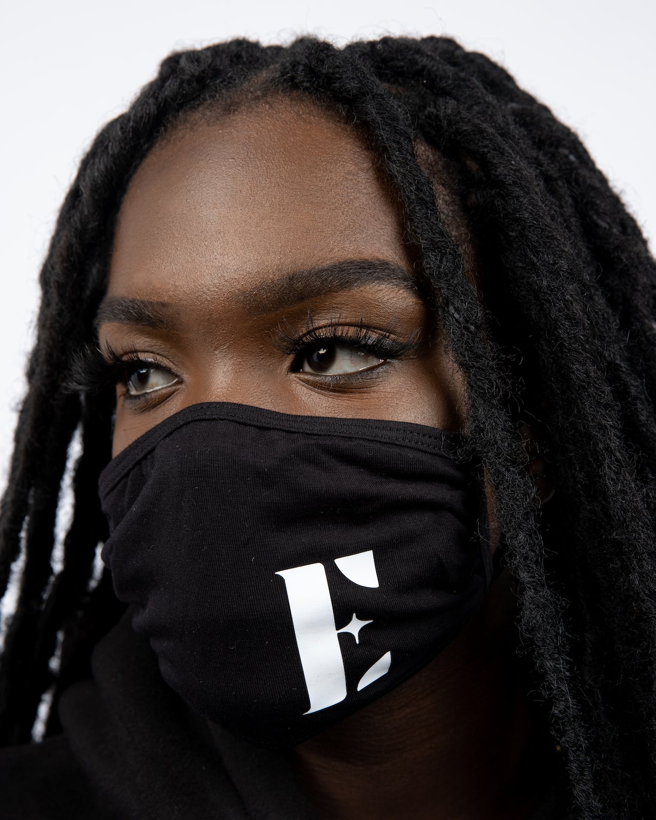 Model wearing a black reusable face mask. The face mask has the E's Element logo imprinted in white. Smoky Black Face Mask by E's Element.