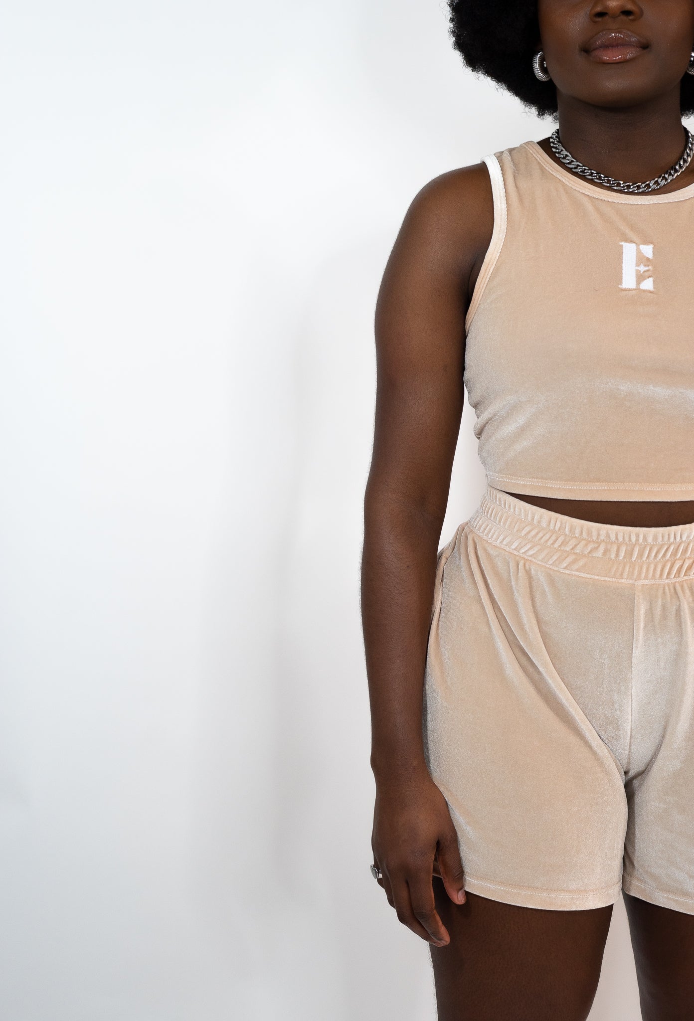 Model wearing beige tank top and shorts. The tank top has the E's Element logo imprinted in white in the middle. Ella Champagne Velvet Set by E's Element.