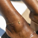 Model wearing an 18k gold anklet with a heart shaped charm. Ella's Element Heart Charm Anklet by E's Element.