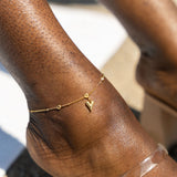 Model wearing an 18k gold anklet with a heart shaped charm. Ella's Element Heart Charm Anklet by E's Element.