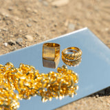 Two 18k gold stainless steel rings and a necklace resting on top of a mirror. Build Your Own Jewelry Set by E's Element.
