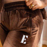 Model wearing dark brown crop top and joggers. The jogger has the E's Element logo imprinted in white. She is also wearing 18k gold rings on her index and ring finger. 