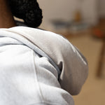 Woman wearing a light grey hoodie. The hoodie is a part of the Essential Light Grey Sweatsuit Set by E's Element.