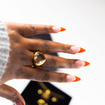 Model wearing an 18k gold ring with a heart shaped gem on the middle finger. Ella White Gemstone Ring by E's Element.
