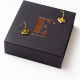 18k gold solid heart drop earrings placed on its container. The container is black with the E's Element logo imprinted in gold in the center. Ella Drop Hook Heart Earring by E's Element.