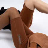 Two models laying down. The model in front is wearing a brown hoodie. The model in the back is wearing a black hoodie. Both of the models are wearing brown biker shorts. The Ella Shaping Cycling Shorts (Petite Size) by E's Element.