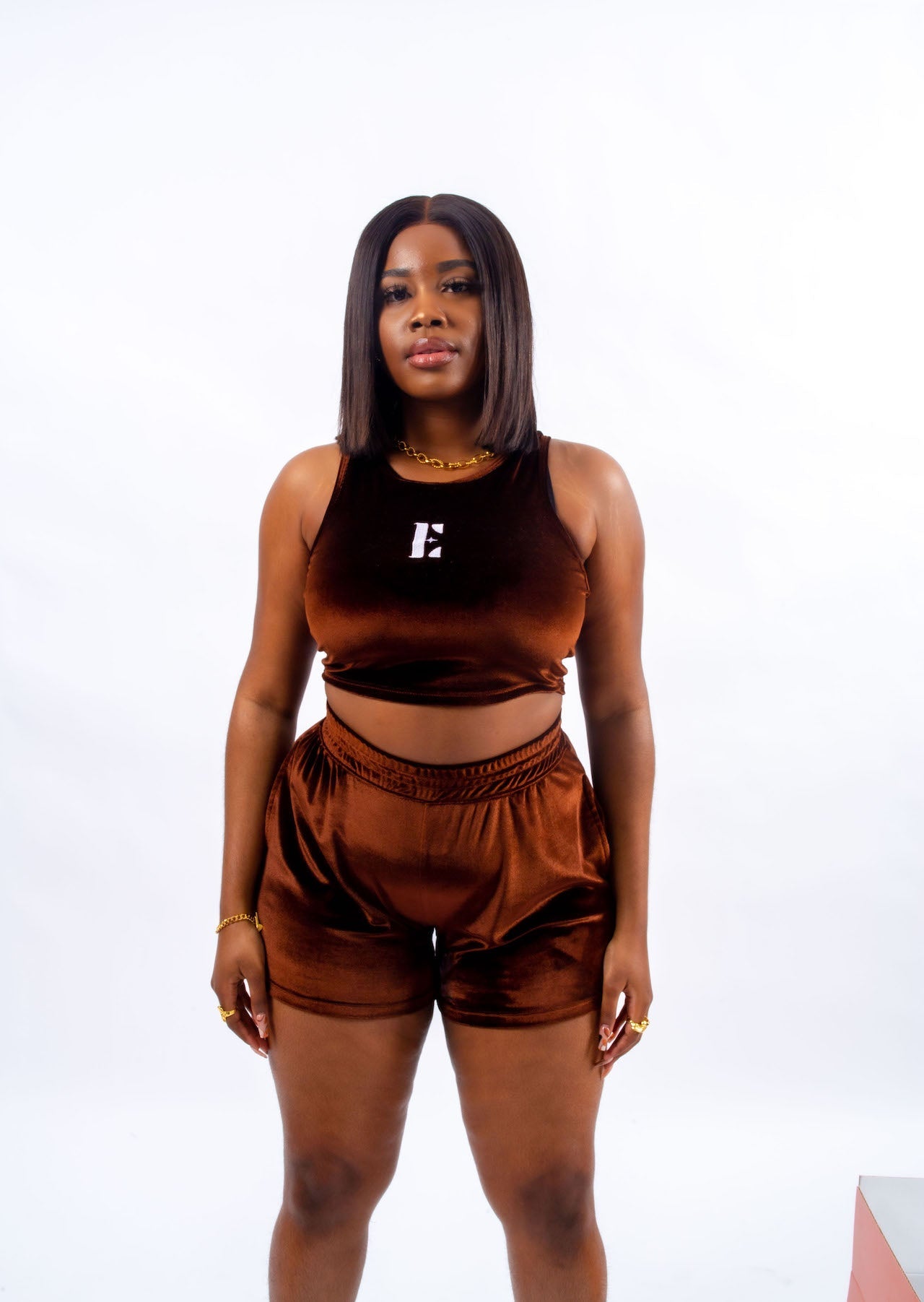 Model wearing velvet dark brown crop top and shorts. The crop top has the E's Element logo imprinted in the middle in white. The model is also wearing 18k gold chain accessories. Ella Chocolate Velvet Set by E's Element.