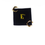 18k gold stainless steel hoop earrings resting on top of a polishing cloth with E's Element logo printed in gold. Angel Hoops by E's Element.