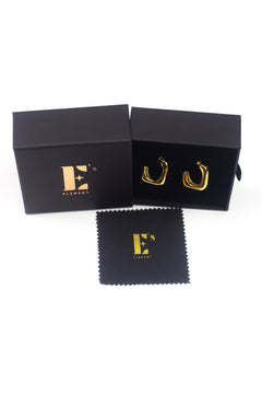 18k gold stainless steel hoop earrings resting on top of its container. There is a polishing cloth underneath with E's Element logo printed in gold. Angel Hoops by E's Element.