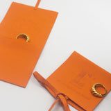 18k gold croissant shaped rings placed in orange leather pouches. Thick Croissant Rings by E's Element.