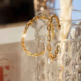 18k gold stainless steel Cubic Zircona hoop earrings hanging on the edge of a glass cup. . Ella Anchor Cubic Zirconia Hoops by E's Element.