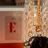 18k gold chain bracelet hanging on the edge of a class cup. Ella Chunky Charm Bracelet by E's Element.
