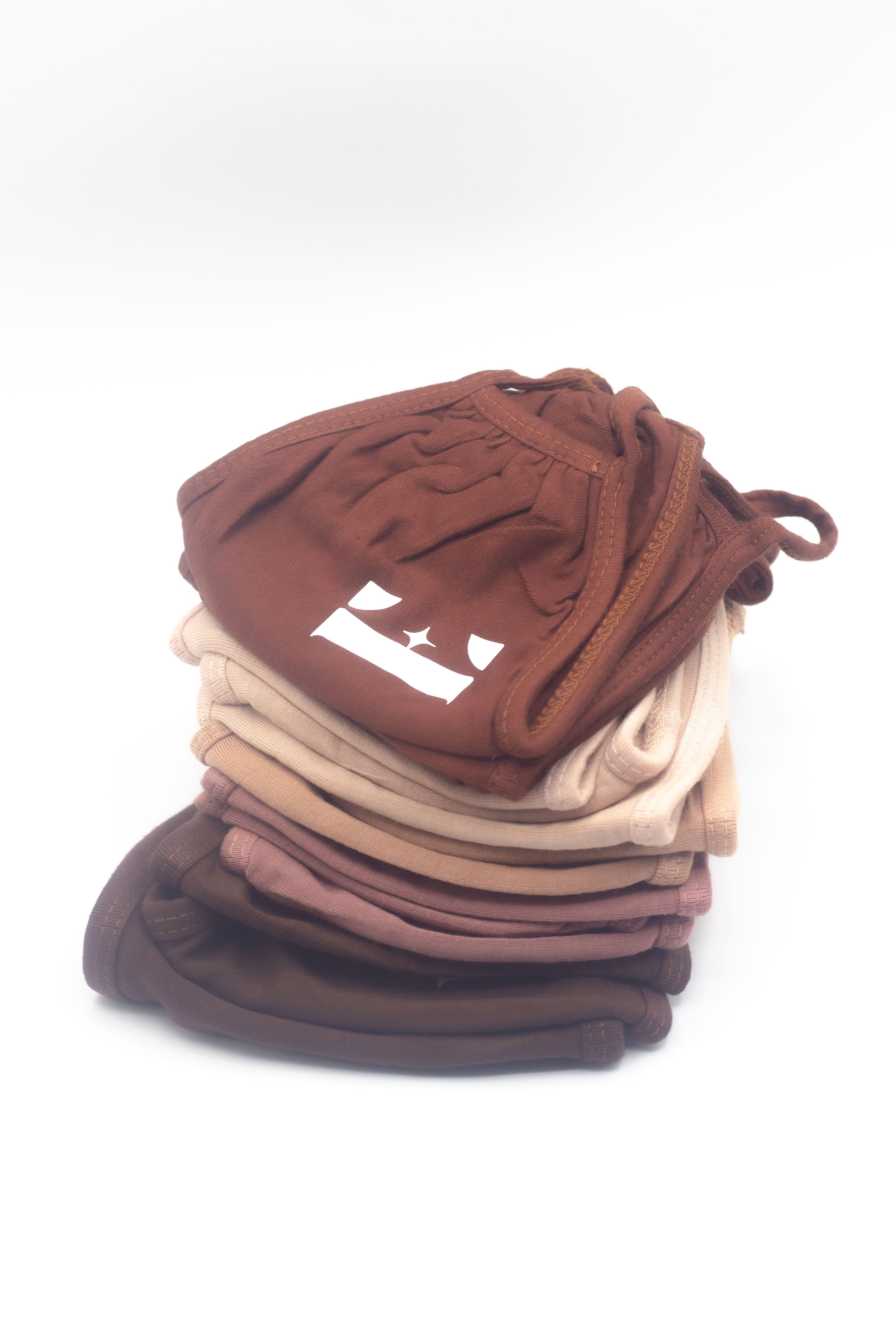From the bottom up, there are dark brown, mauve, light brown, beige, and chocolate coloured face masks stacked on each other.  Reusable Masks (5 Piece) by E's Element.