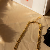18k gold chain necklace placed on a beige cloth. Above the necklace is a white box with the E's Element imprinted in red. Ella Figaro Necklace by E's Element.