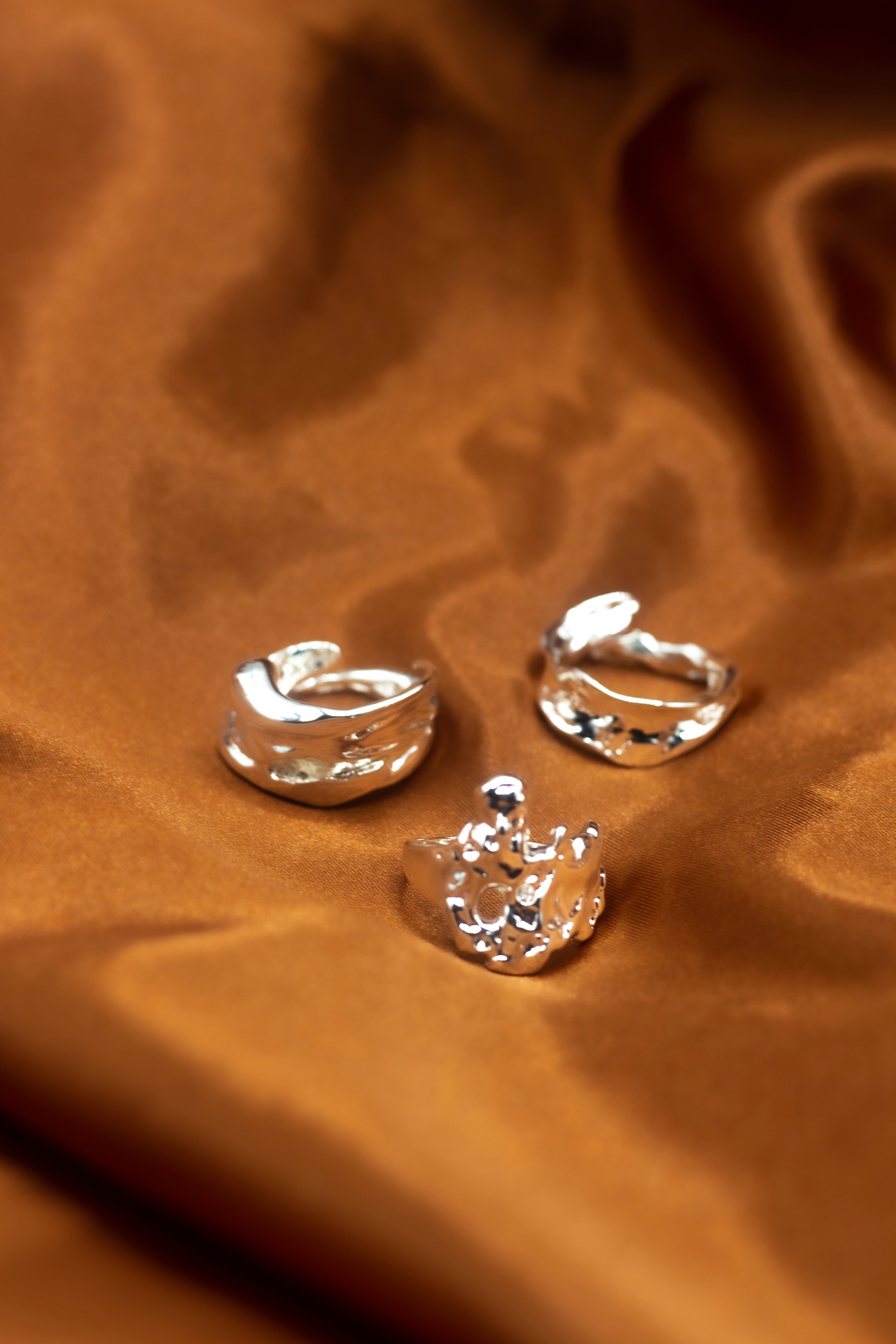 18k silver molten rings placed on an orange cloth.  Ella Lava Ring Trio (Set of 3) by E's Element.