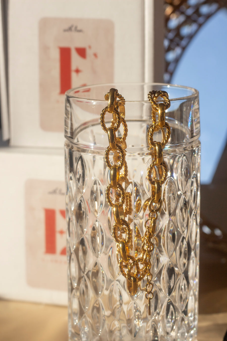 18k gold chain necklace with a rope pattern. The necklace is hanging on the edge of a glass cup. Rope Link Signature Chain by E's Element.