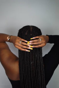 Back shot of a model in a black top wearing 18k gold ring with white baguettes. The model is also wearing a watch. Ella Tennis Ring by E's Element.
