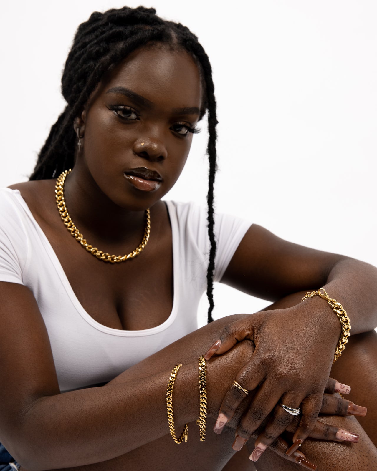 Model in a white top wearing 18k gold chain necklace and bracelets. The Emmanuela Set in Gold by E's Element.